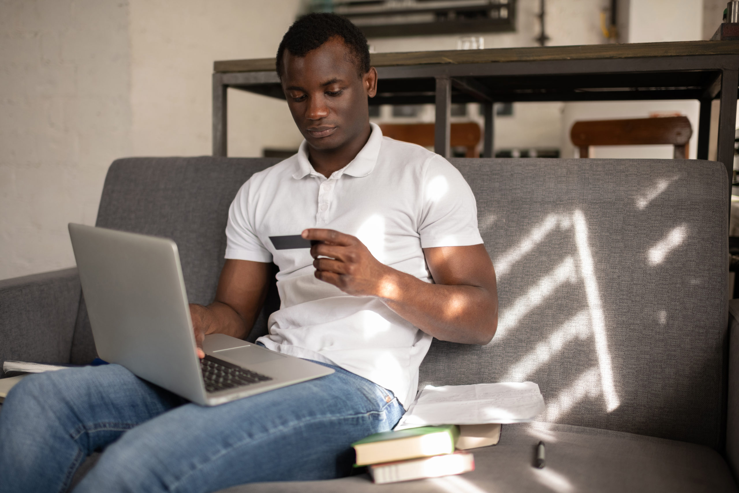 African American student shopping online sitting on sofa